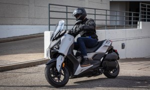 2024 Yamaha XMAX scooter left fron tthree-quarter shot driving up an incline from an underground parking lot.