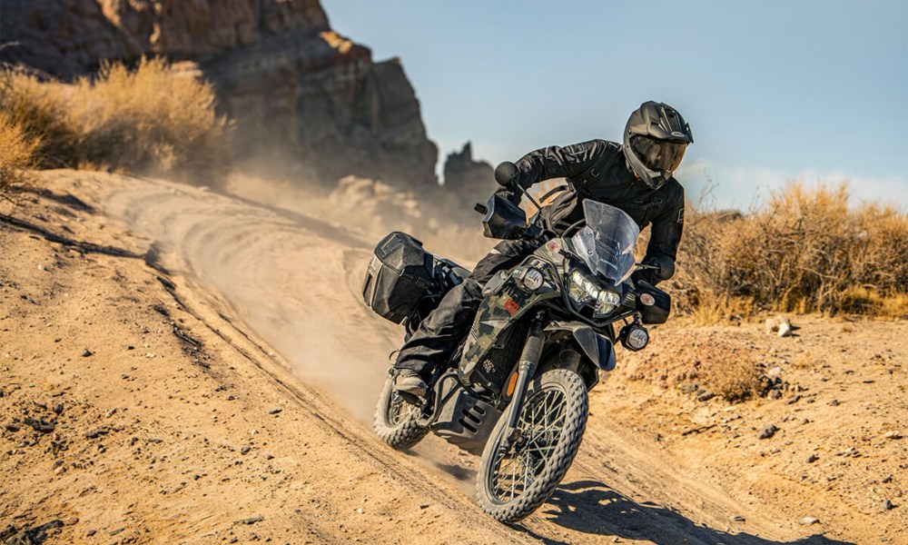 2025 Kawasaki KLR 650 Adventure ABS right front three-quarter view descendng a dirt road.