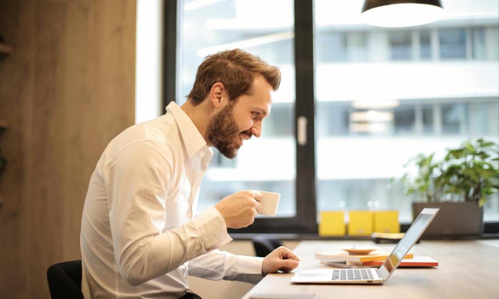 Man drinking coffee while working on a laptop