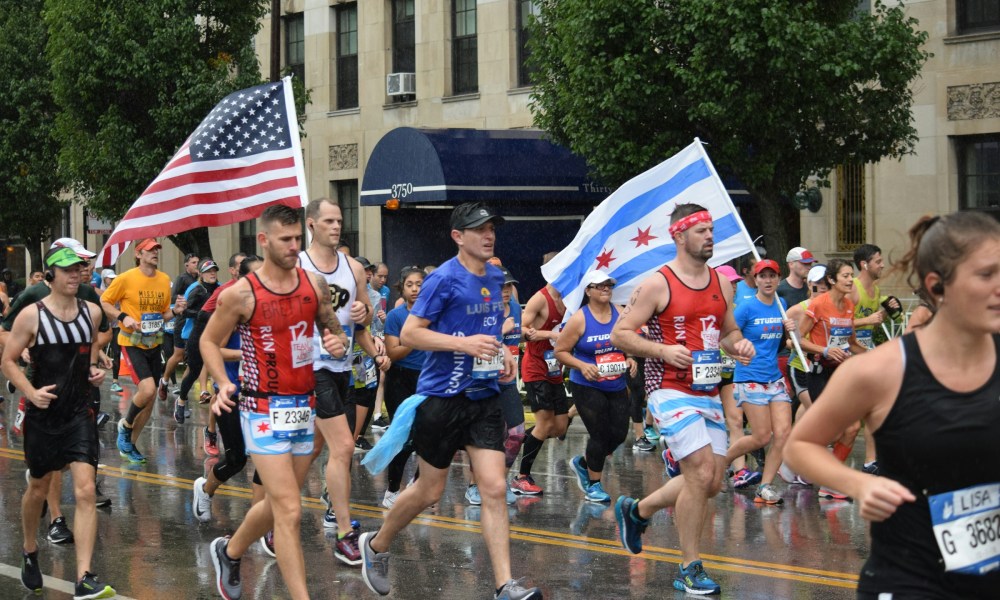 men running in marathon with US flag rainy