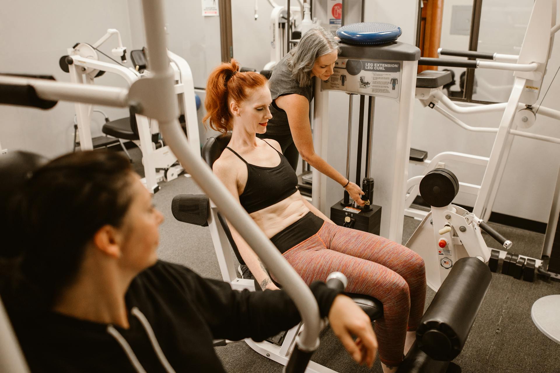 Two women performing leg press and knee extension exercises