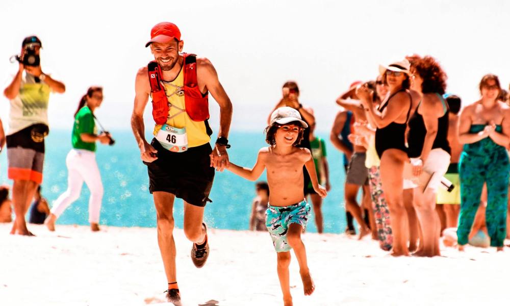 man and son running a marathon together outside on beach