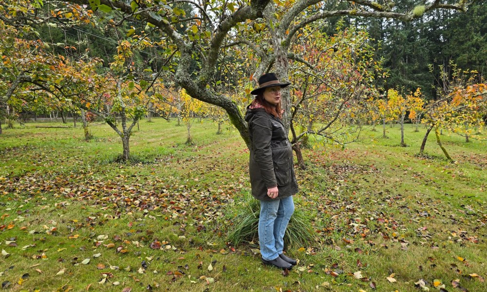 The owner of Nashi Orchards standing under an apple tree on her property