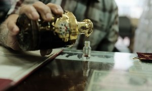 A merchant pours a sample vial of fragrance