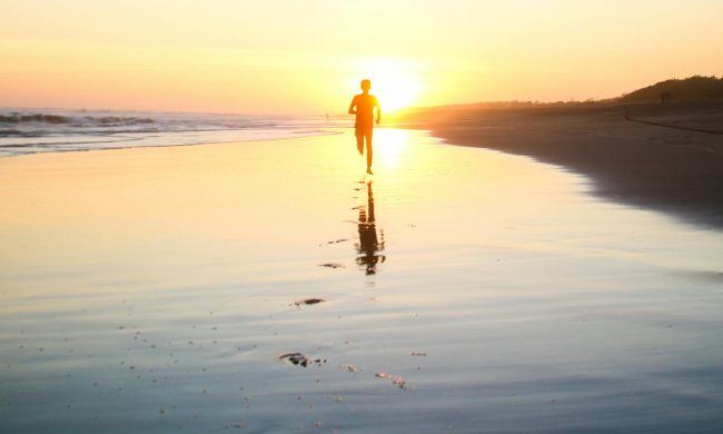 Man running on the beach at sunset