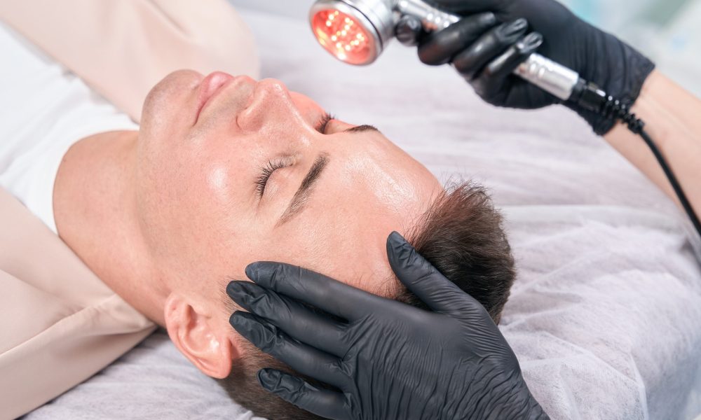 Relaxed man lying on treatment bed during red light therapy