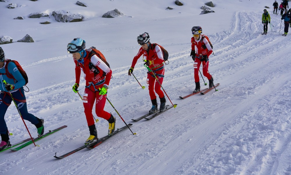 A group of men in red jackets cross country skiing on a groomed trail